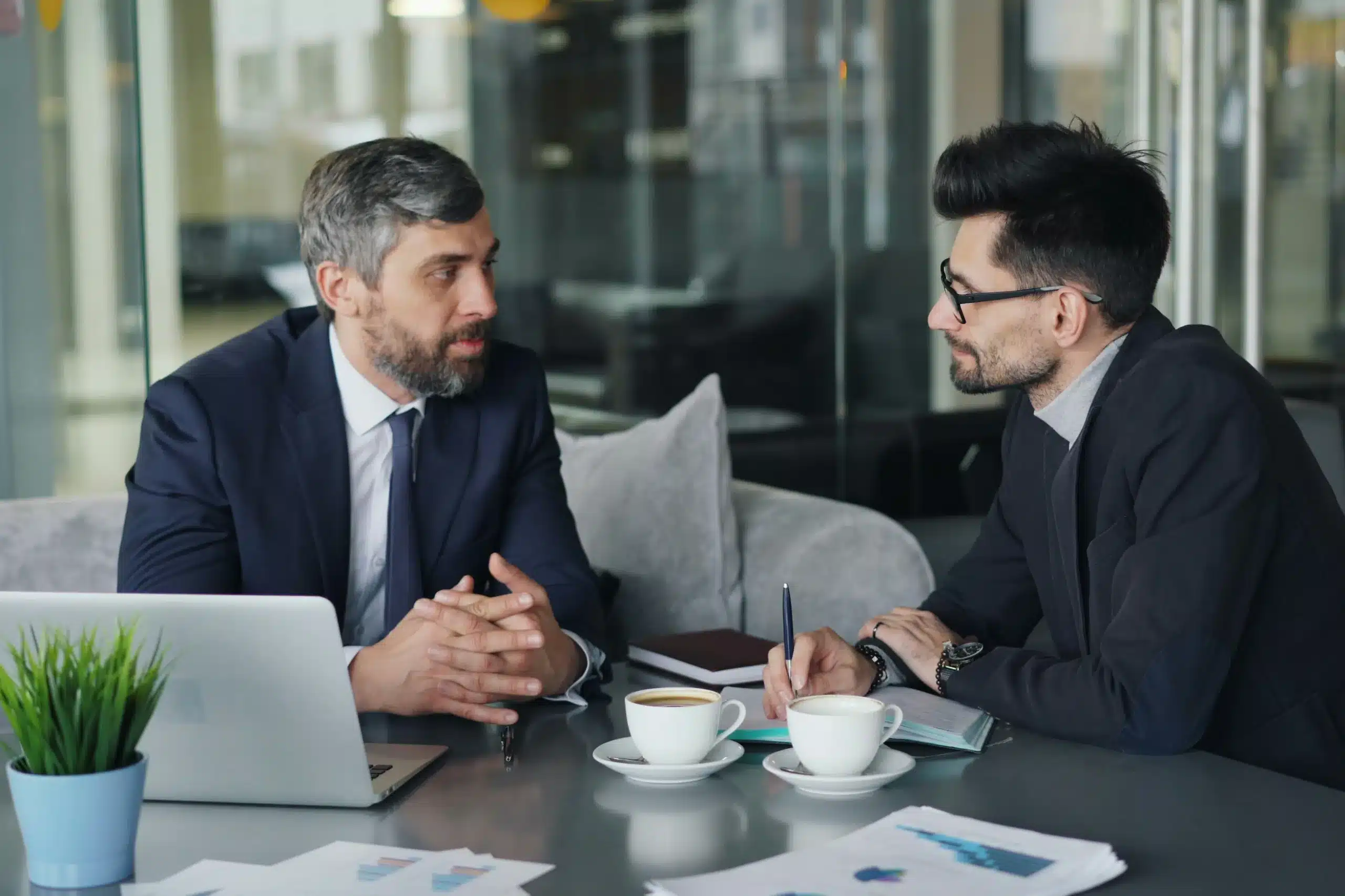Dos ejecutivos de distintas generaciones conversando en una oficina sobre el relevo generacional